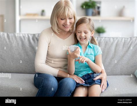 Portrait Of Happy Mature Woman And Granddaughter Using Phone Stock Photo Alamy