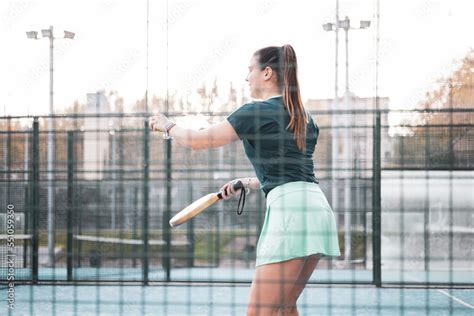 a beautiful young woman about to take a serve in a paddle tennis match ...