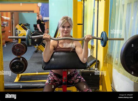 Blonde Exercises Arm Muscles By Lifting Weights At The Gym Stock Photo Alamy