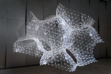 A Sculpture Made Out Of White Wire On Top Of A Black Floor Next To A Wall