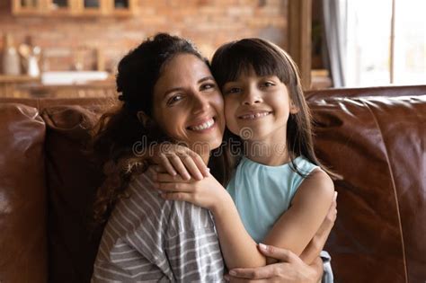 Mãe Latina Solteira Sentada No Sofá a Abraçar a Filha Pequena Imagem de