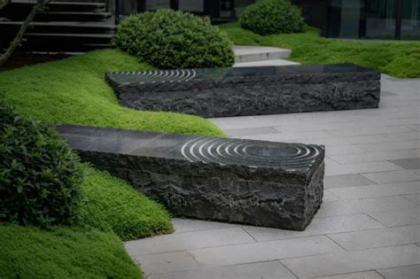 A Stone Bench Sitting In The Middle Of A Garden With Grass Growing On