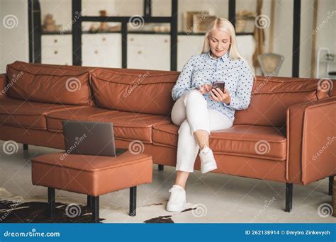 Good Looking Blonde Woman Sitting On The Leather Sofa At Home Stock Photo Image Of Connetced