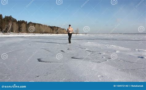 Man In A Cap With A Naked Torso Running Across The Ice Of A Frozen River Stock Footage Video