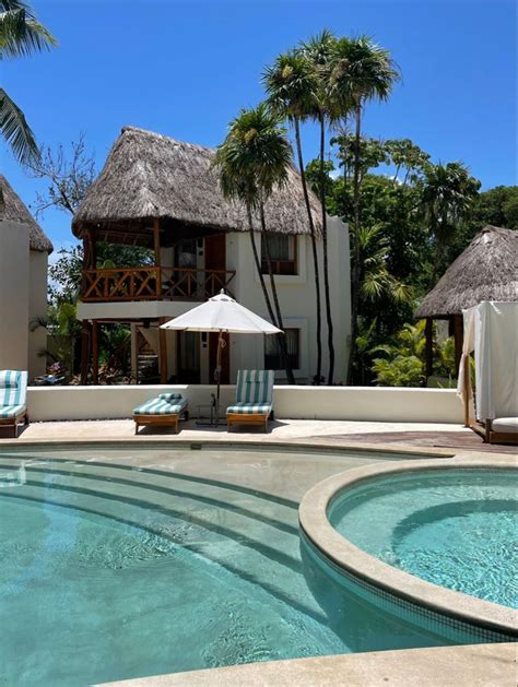 An Outdoor Swimming Pool With Lounge Chairs And Thatched Umbrellas Next