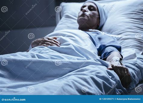 Sick Woman Lying In Hospital Bed With Venflon On Hand During