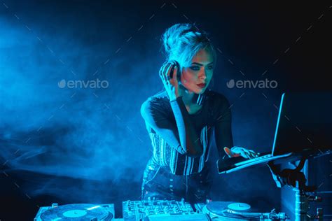 Serious Dj Woman With Blonde Hair Looking At Laptop While Listening Music In Headphones In