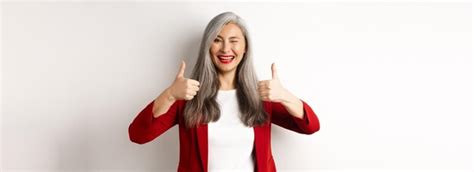 Enthousiaste Femme Mature Asiatique Clignant De L œil Souriant Heureux Et Montrant Le Pouce Levé