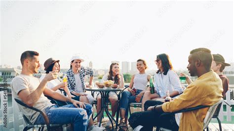 Multiracial group of friends is having open air party drinking, talking ...