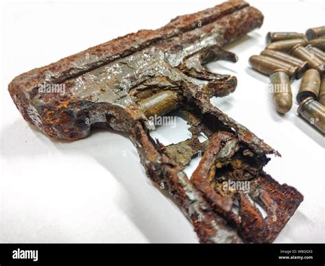 Close Up Of Damaged Rusty Metallic Gun With Bullets On White Background