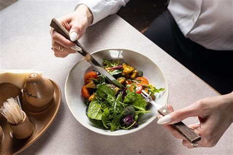 Premium Photo A Person Eating A Salad With A Fork And Knife