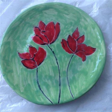 A Green Plate With Red Flowers Painted On It