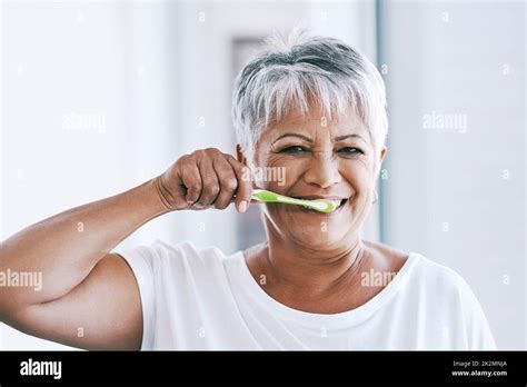Early Morning Routines Portrait Of A Cheerful Mature Woman Brushing Her Teeth While Looking At