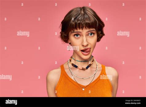 Cheeky Playful Girl In S With Short Brunette Hair Sticking Tongue Out On Pink Background Stock