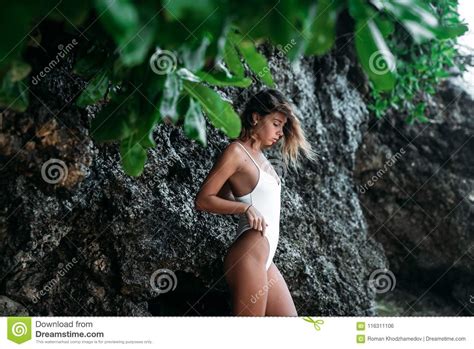 Portrait Of A Brunette Girl In A White Swimsuit Near A Rock Beautiful Model On Summer Vacation
