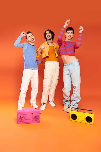 Premium Photo Three Joyful Attractive Gay Friends In Vivid Attire Posing With Tape Recorders