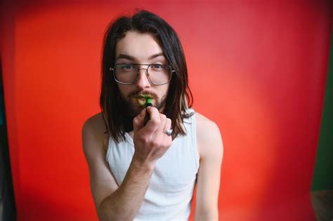 Joven aplicando brillo de labios en sus labios y mirando a la cámara como un espejo hombre gay