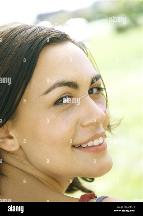 Young Woman Looking Over Shoulder Smiling At Camera Stock Photo Alamy