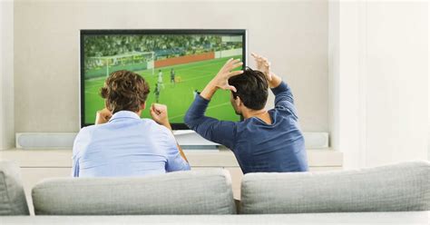 Men watching soccer game on sofa stock photo