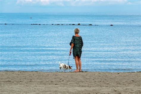 Mujer Con Perro En La Playa Foto Premium