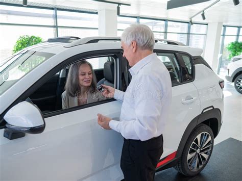 Mature Caucasian Woman Sits In A New Car An Elderly Man Gives Her The Keys Stock Image Image