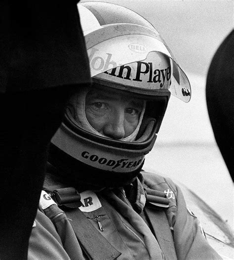 A Black And White Photo Of A Man In A Racing Suit With A Helmet On