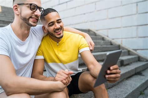 Retrato de casal gay feliz passando algum tempo juntos enquanto está sentado na escada ao ar
