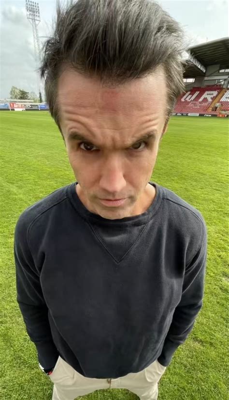 A Man Standing On Top Of A Lush Green Field Next To A Soccer Field And