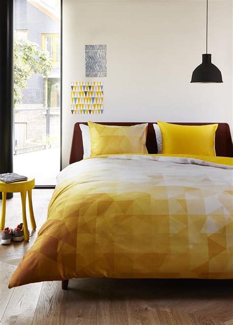 A Bed With Yellow Comforters And Pillows In A Bedroom Next To A Large