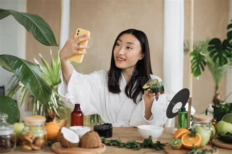 Asian Brunette Shoulder Length Hair Female Social Media Influencer Holding Glass Jar With Cream