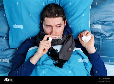 Sick Brunet Man Using Nasal Spray While Lying In Bed Stock Photo Alamy