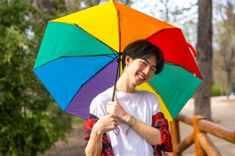 Premium Photo Cute Gay Chinese Man Smiling Holding A Rainbow Colored Umbrella