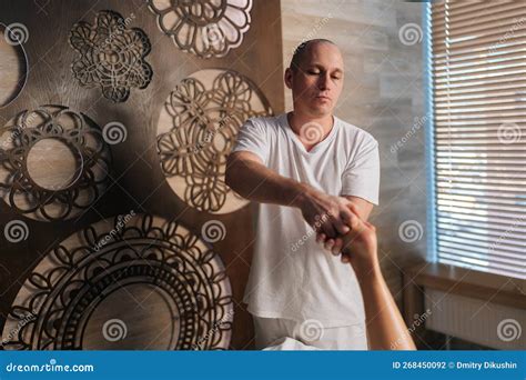 Portrait Of Professional Male Masseur Massaging Heel Of Foot Of