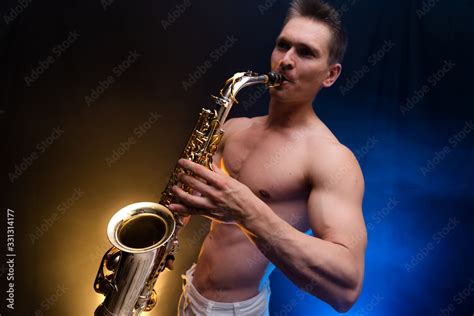 Muscular Man With Naked Torso Playing On Saxophone With Smoked Colorful Background Stock Photo