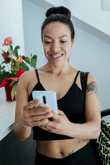 Chica Latina Y Deportiva Usando Su Celular En El Gimnasio Mirando Sus