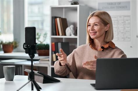 Enseignante Mature Souriante Utilisant Un Smartphone Pour Un Cours En Ligne Avec Ses élèves