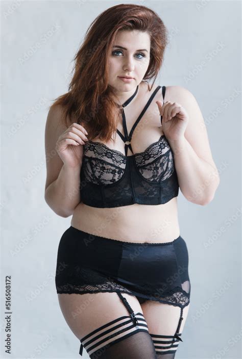 A Plus Size Model In Lacy Black Lingerie Poses In A Bright Room With A Trendy Interior
