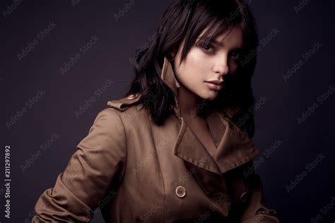 Dark Portrait Of Beautiful Sensual Woman With Nude Makeup Dark Hair Wearing Beige Trench Coat