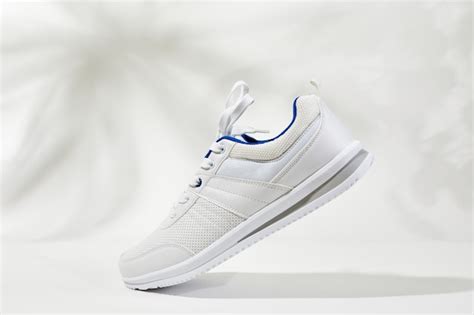 Zapatillas Deportivas Blancas Con Cord N En Una Pared Blanca