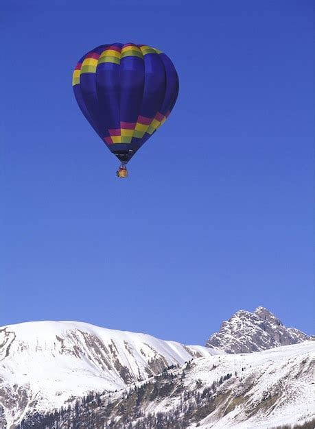 Premium Photo A Hot Air Balloon Is Flying Over A Snowy Mountain