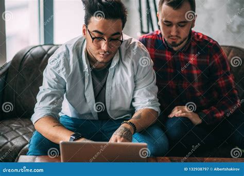 European Gay Male Couple Spend Time Together Drinking Coffee And Watching Laptop Stock Image