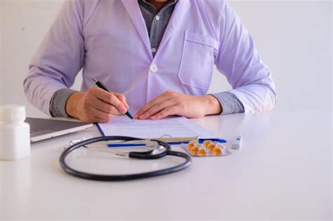 Premium Photo Midsection Of Doctor Writing On Paper At Clinic