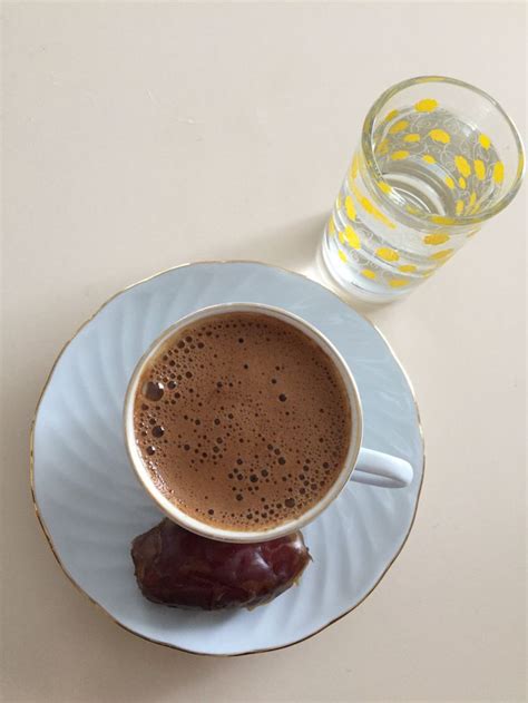 A Cup Of Hot Chocolate Next To A Glass Of Water On A White Plate With