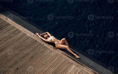 Wooden floor,, lying down, resting. Woman in white bikini is near
