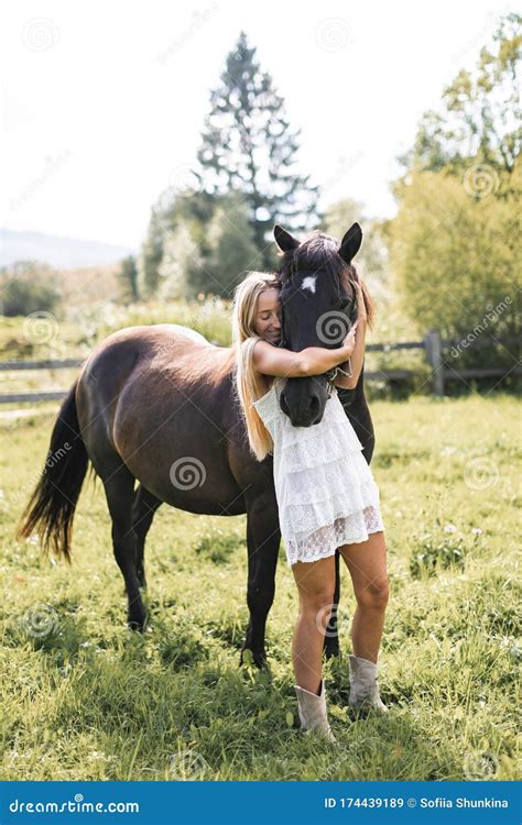 Hübsche Junge Blonde Frau in Weiß Boho Kleid Ihr Pferd Bei Sonnenuntergang Sommerfeld