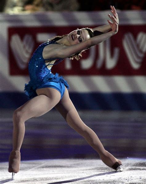 A Female Figure Skating On The Ice In A Blue Leotard Suit And Black Shoes