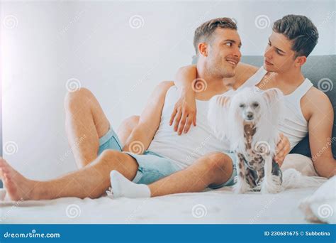Jeune Couple Gay Qui Rit Et Se Serre Dans Son Lit Hommes Heureux Et Leur Chien S Amusant