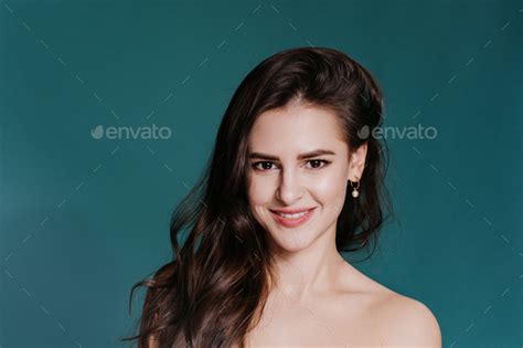 Close Up Of Naked Adorable Beauty Model Smiles Wide Looks At Camera Over Dark Blue Studio