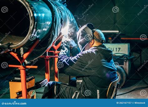 Shallow Focus Of A Welder Wearing A Protective Helmet And Welding Steel
