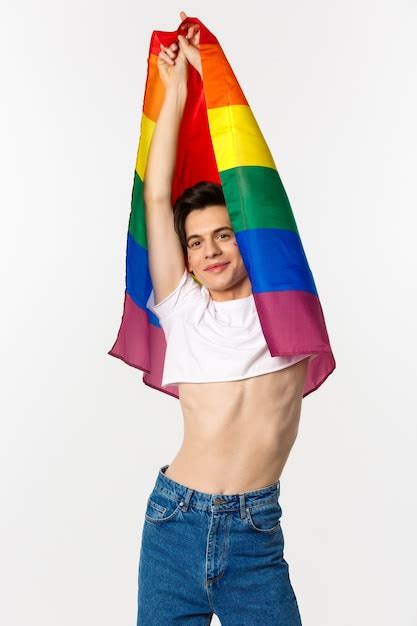 Premium Photo Vertical View Of Beautiful Androgynous Gay Man Raising Rainbow Flag And Smiling